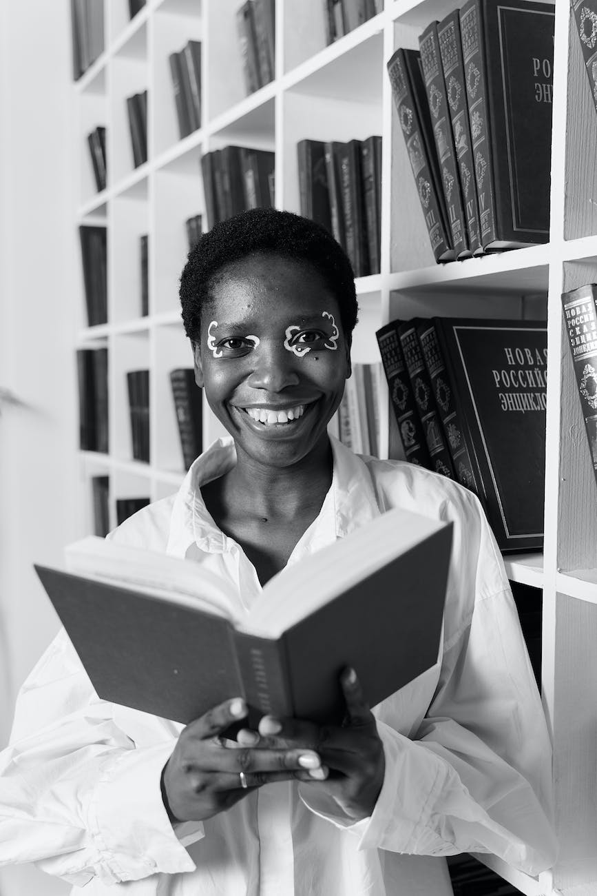 grayscale photo of woman in white collared shirt holding a book
